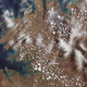 White specs and clouds dot over remote coastal islands and inlets of the Kimberly region of Western Australia in the color, surrounded by the Indian Ocean.